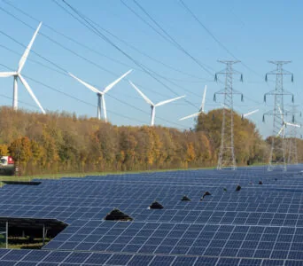 Renewable energy sources and infrastructure: wind turbines, solar panels, and power lines in one landscape.